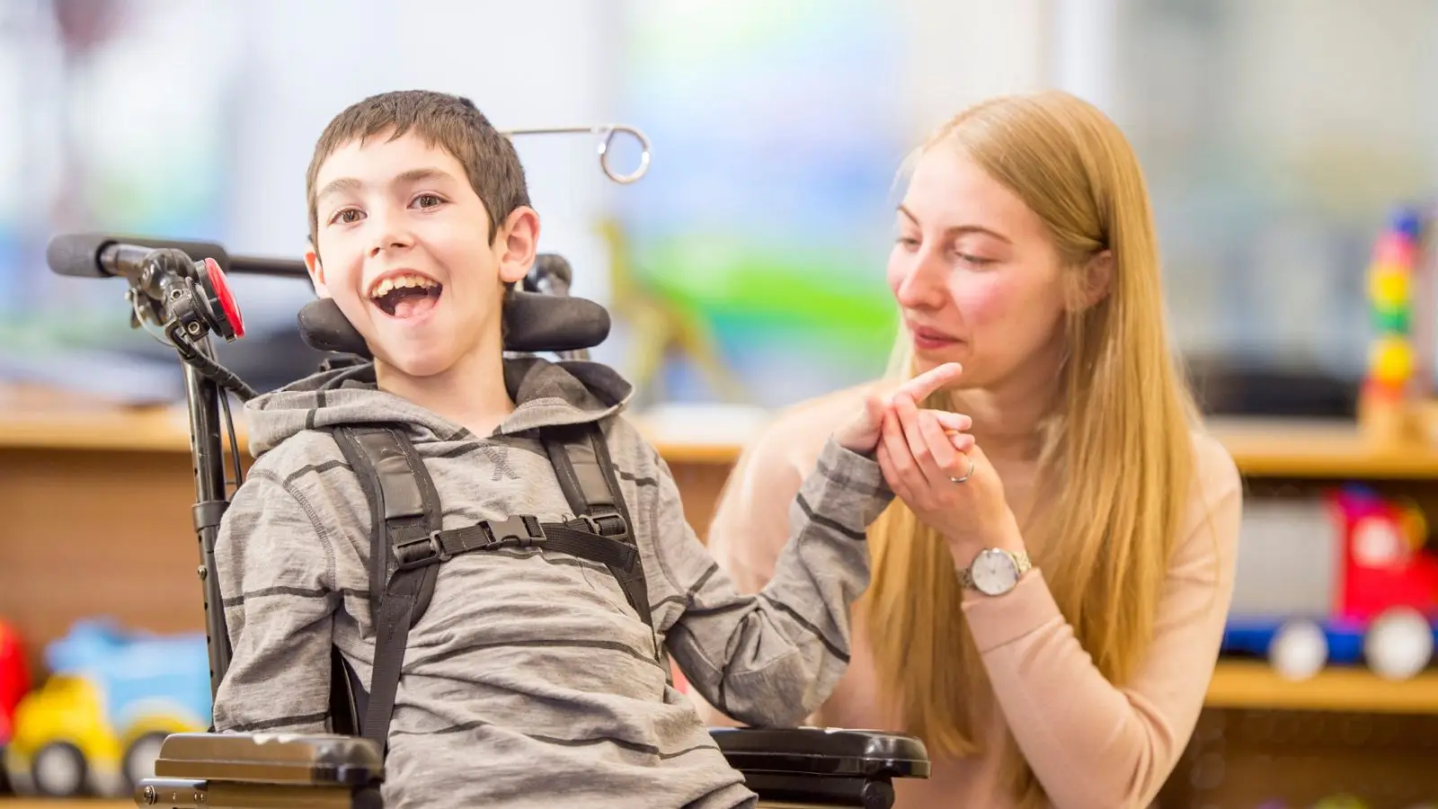 Un accompagnant et un enfant en fauteuil roulant echangent, dans une salle de jeux