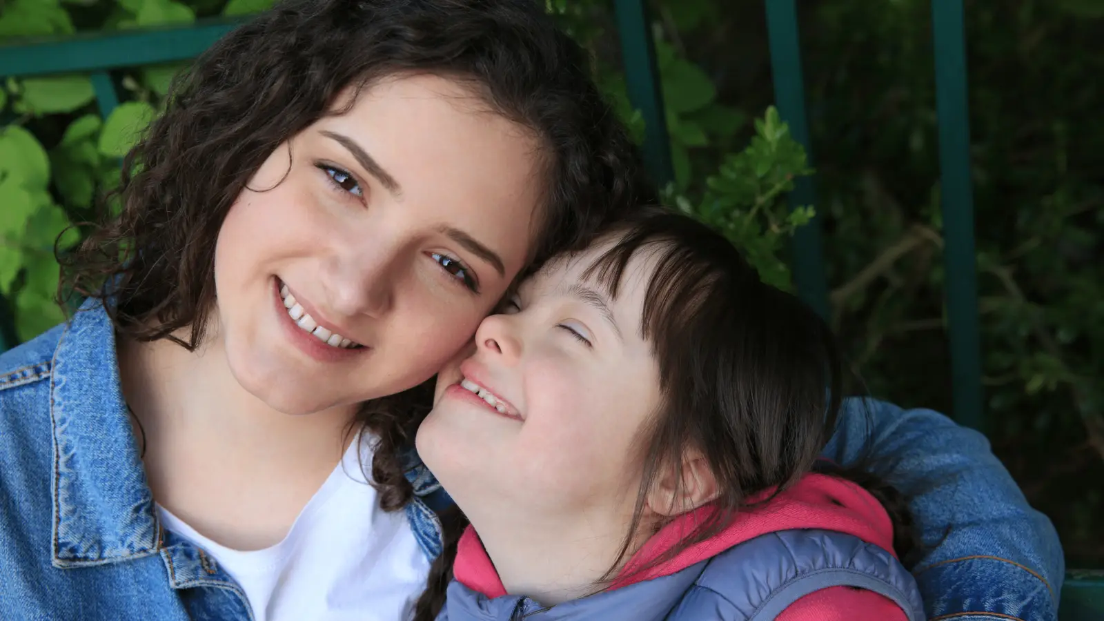 Une accompagnante et un enfant assis côte à côte, souriants